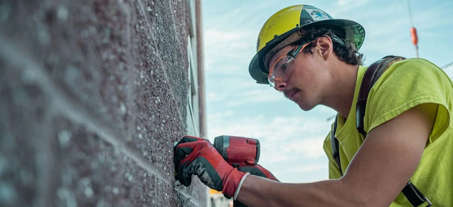 Man with safety glasses drilling into wall