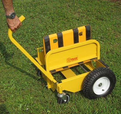 Yellow two wheeled hand cart with long handle being pushed on grass