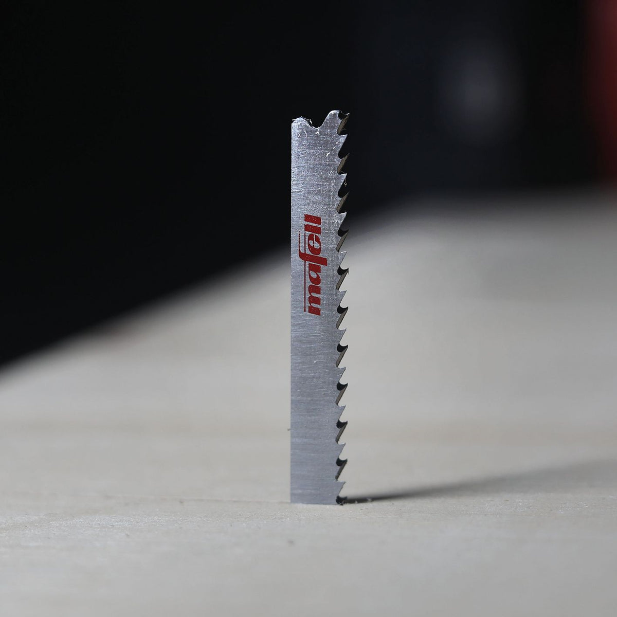 Close-up of Mafell W6 reverse-cut jigsaw blade showing upward teeth and red Mafell branding.