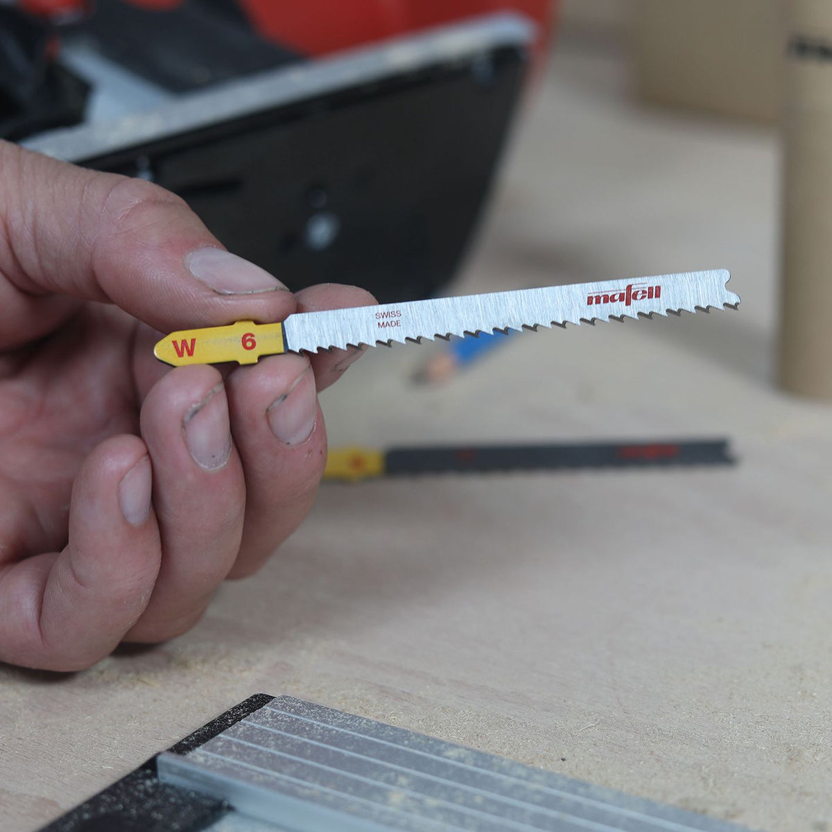 Hand holding Mafell W6 reverse-cut blade with yellow end and red Mafell logo.