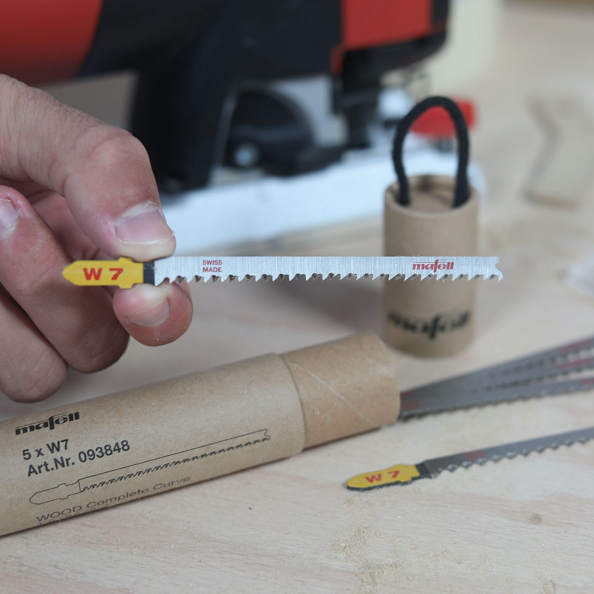 Mafell W7 wood complete curve blade held horizontally with yellow tip and Mafell logo, on a workshop table.