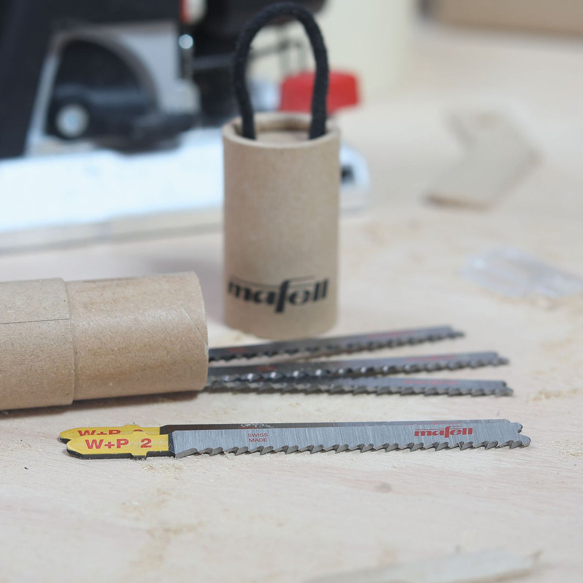 Mafell W+P2 jigsaw blades laid out on a workbench with a cardboard Mafell tube in the background.