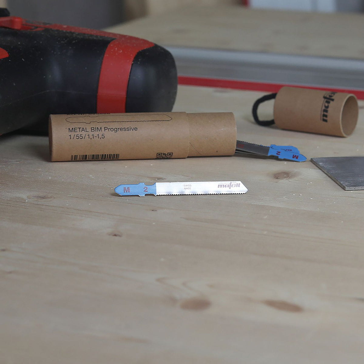 Mafell SSB M2 metal progressive BIM jigsaw blade packaging with five blades on a workbench and a red Mafell case in the background.