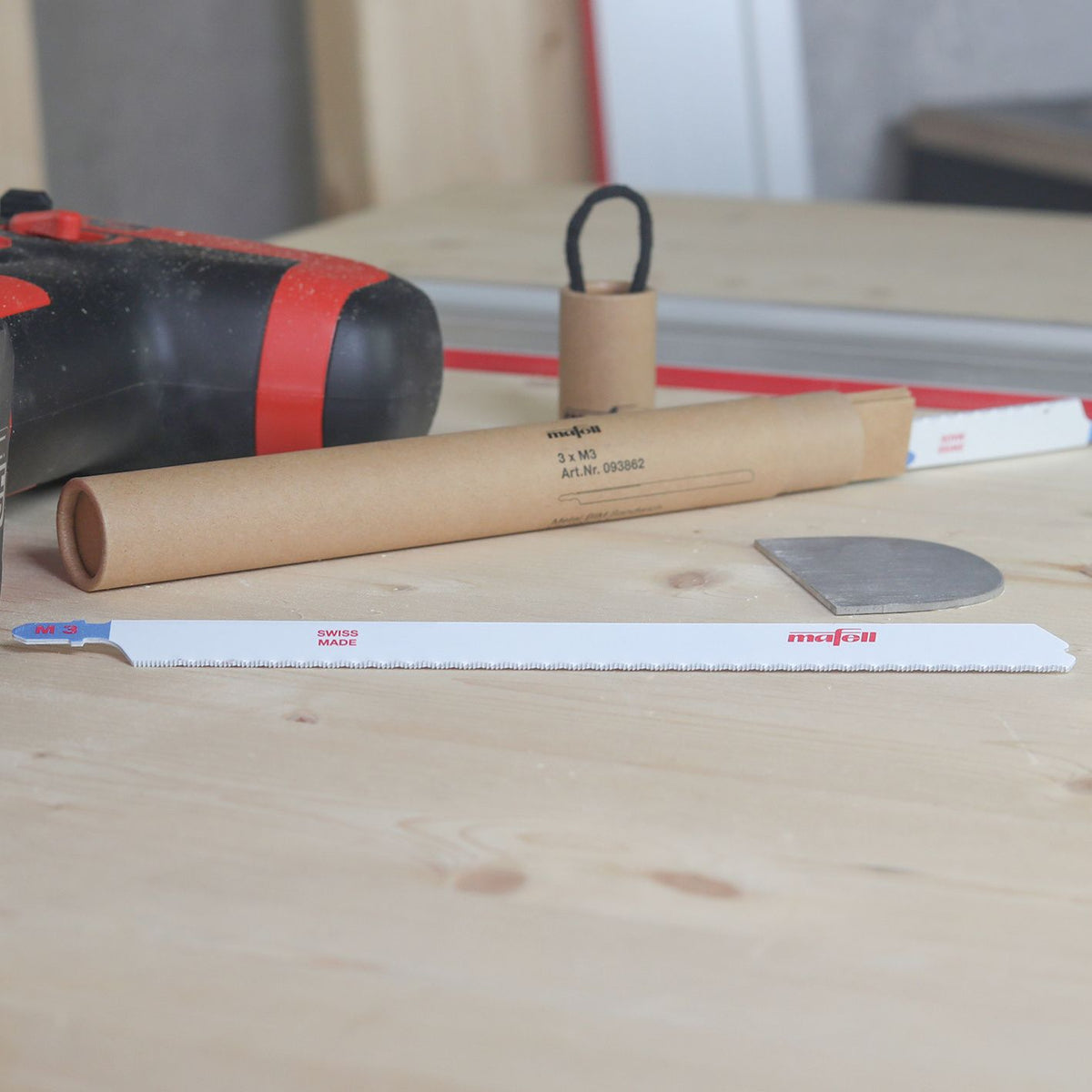 Mafell SSB M3 metal sandwich BIM jigsaw blades 3-pack with a cardboard packaging tube on a wooden workbench