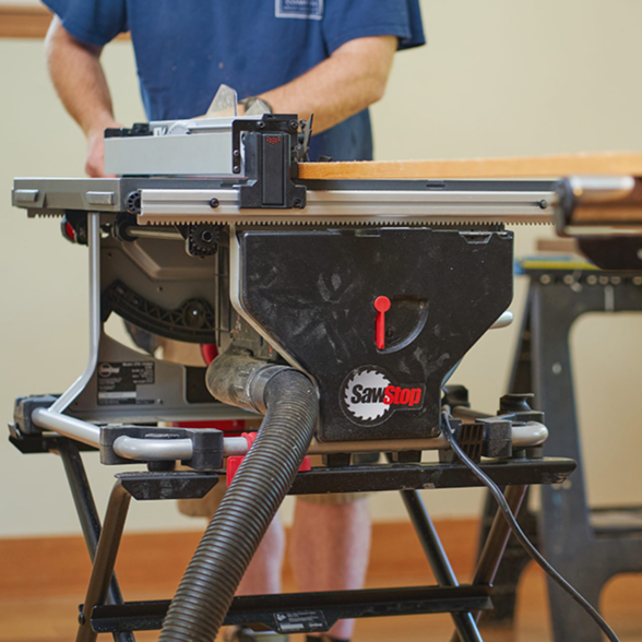 Person using a table saw with 'SawStop' branding in a workshop setting.