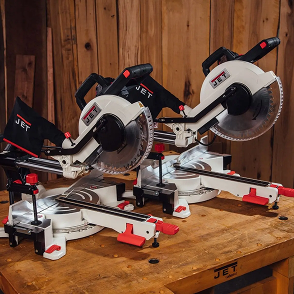 Two JET miter saws on a wooden workbench with a wooden wall background.