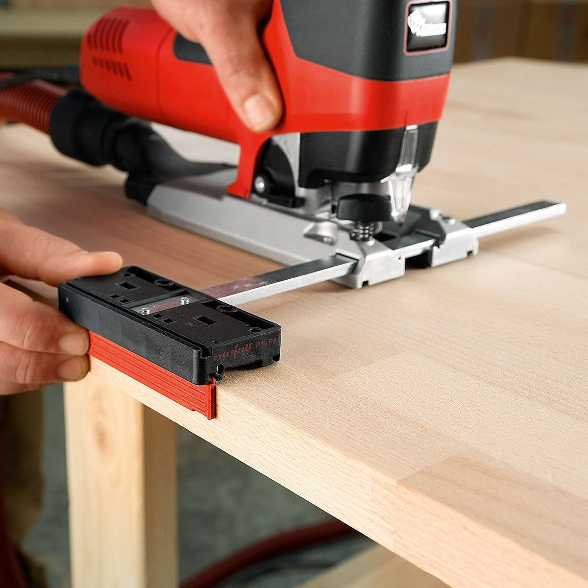 Jigsaw with Mafell parallel guide fence mounted to a track being used to cut a wooden board