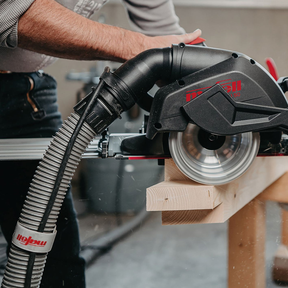 Close up of Mafell cable clips attached to a dust extraction hose beside a power tool