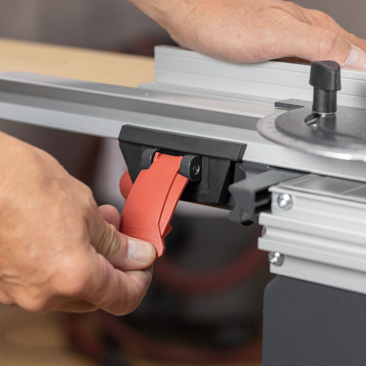 Hands adjust the Mafell guide fence clamp with a red release lever on a silver guide rail.