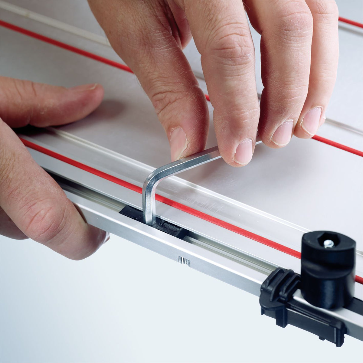 Close up of hands adjusting Mafell Guide Track L with a hex key on a metal guide rail
