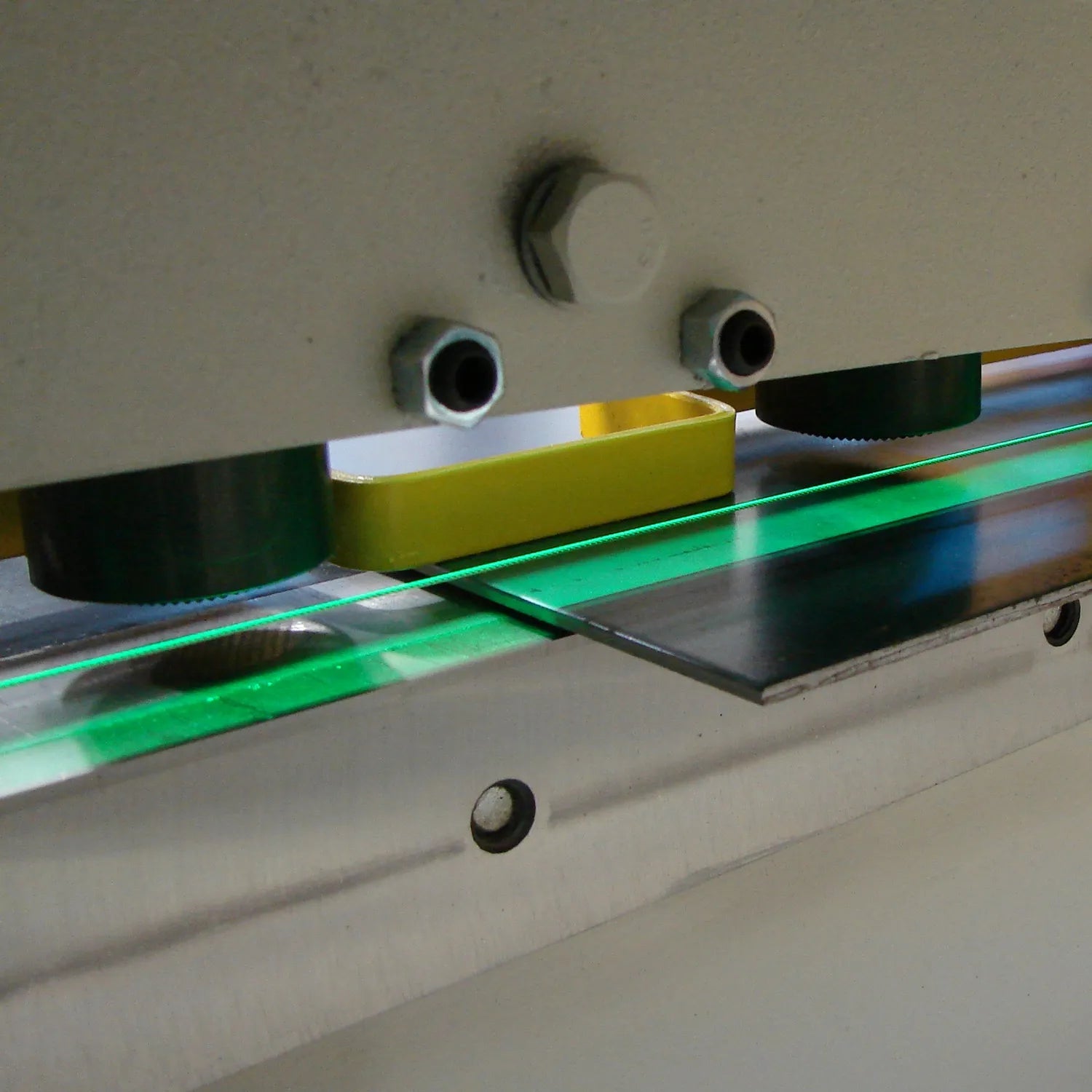 Close-up of the 80 inch sheet metal shear bed area with mounting bolts and a green guiding rail.