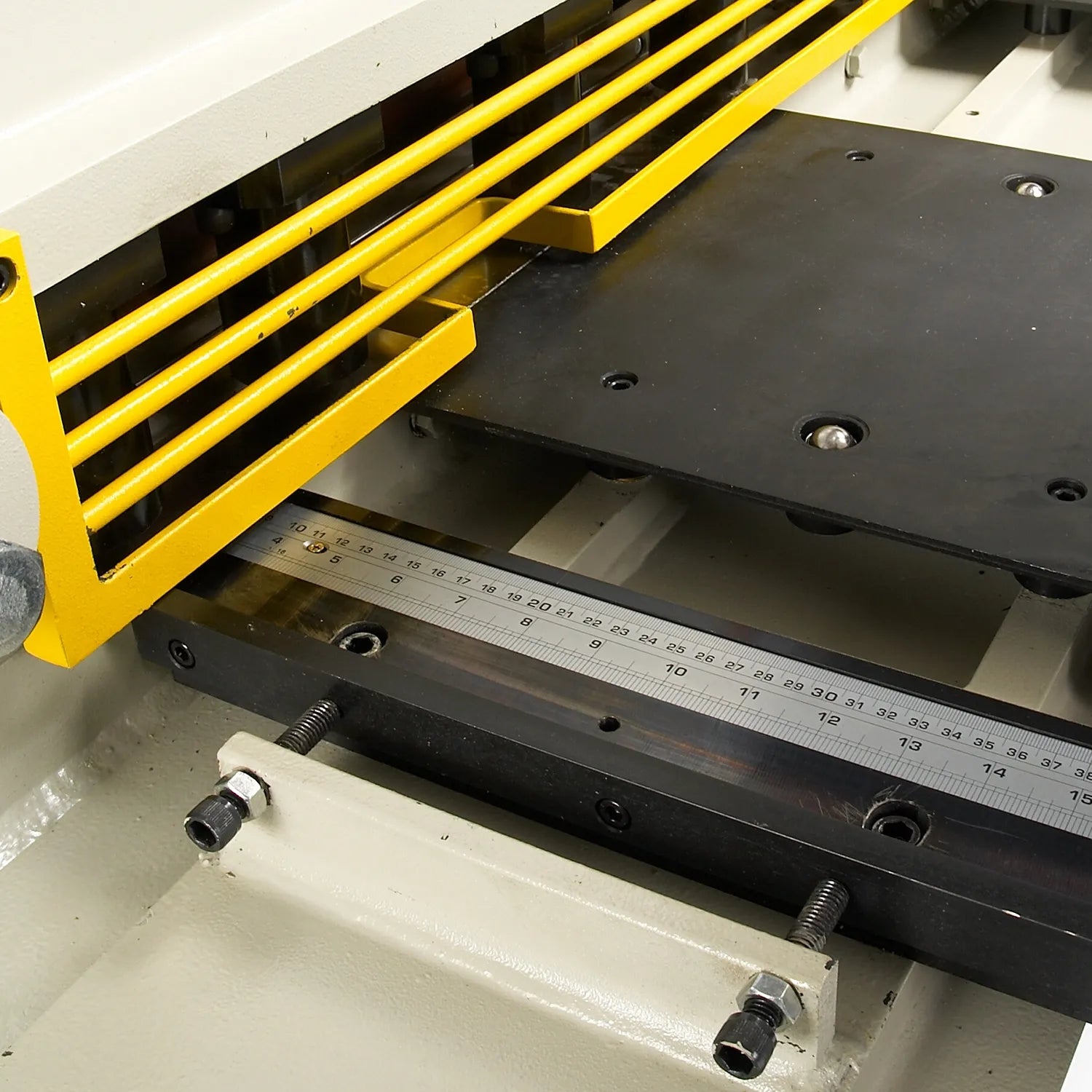 Inside view of the machine bed showing yellow guard rails and a metal ruler along the edge.