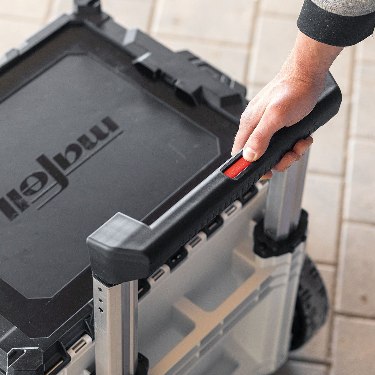 Hand gripping the telescoping handle of a Mafell L-BOXX Contractor transport case with NFU 50 insert.