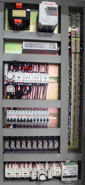 Inside an electrical control cabinet showing circuit breakers, relays, terminal strips and wiring.