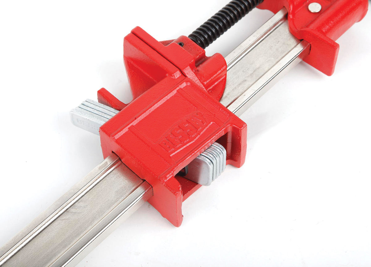 Close-up of red Bessey I-Beam Bar Clamp gripping a silver steel rail