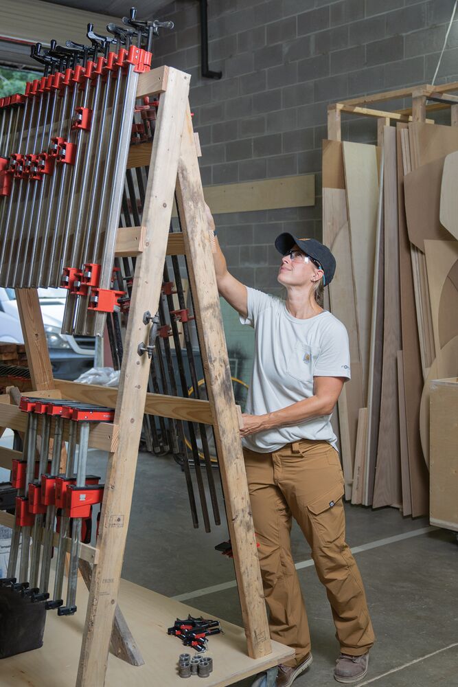 Worker in a workshop inspects a rack of 48 inch Bessey I-Beam bar clamps.