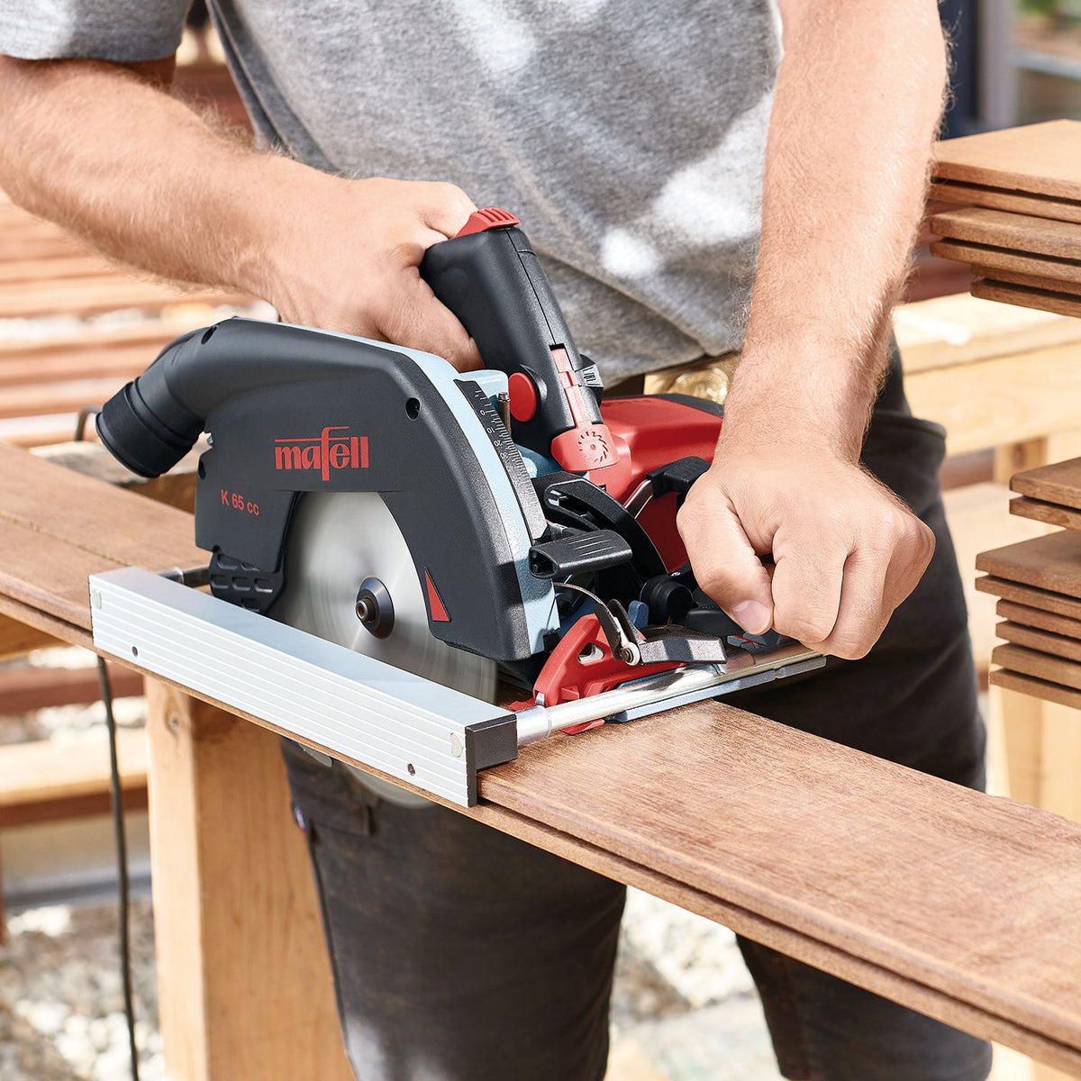 Person using Mafell K 65 cc circular saw with parallel guide fence to cut a wooden board