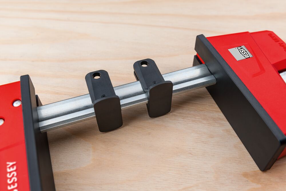 Bessey K Body REVO 12 inch parallel clamp with red housing and black jaws on a wood work surface.