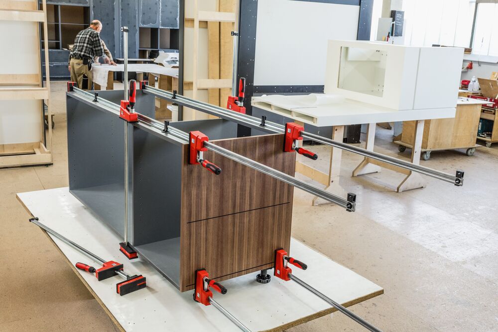 Workshop scene with several Bessey K Body REVO clamps securing a cabinet assembly