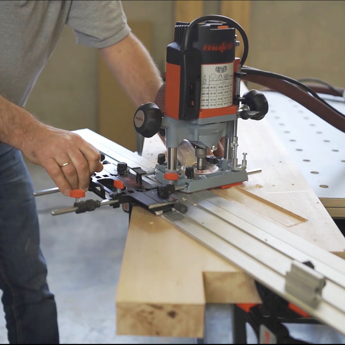 Mafell LO-FA router adapter mounted on a guide rail with parallel fence and adjustable stops on a workbench.