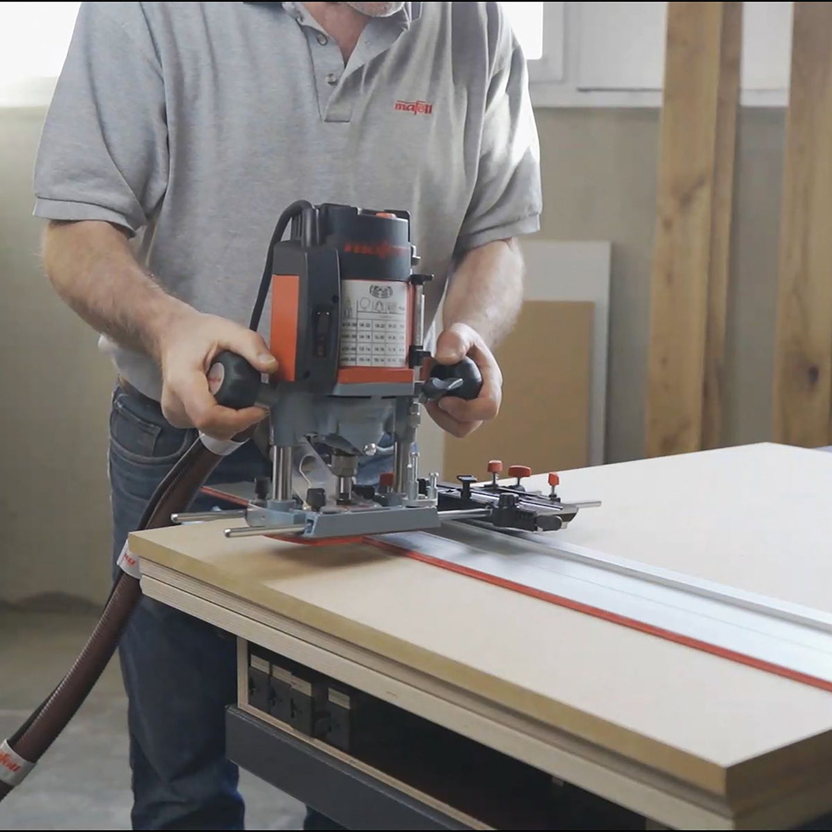 Operator holds the Mafell router adapter ready to use on a guide rail system.