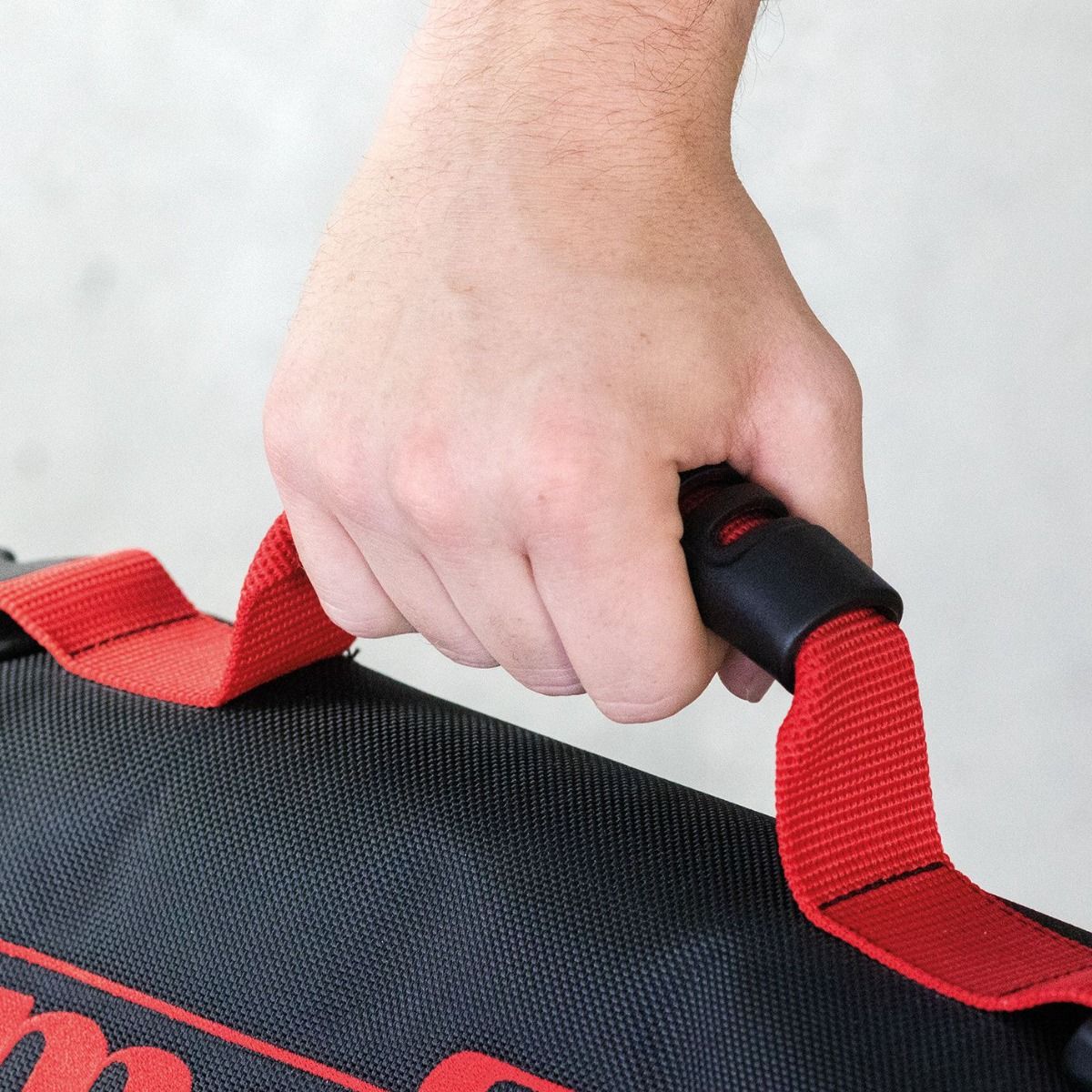 Hand gripping the red carrying strap of the Mafell guide rail bag.