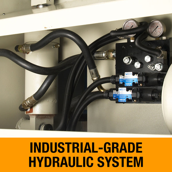 Close-up of an industrial hydraulic system with hoses gauges and a valve block on a sheet metal shear