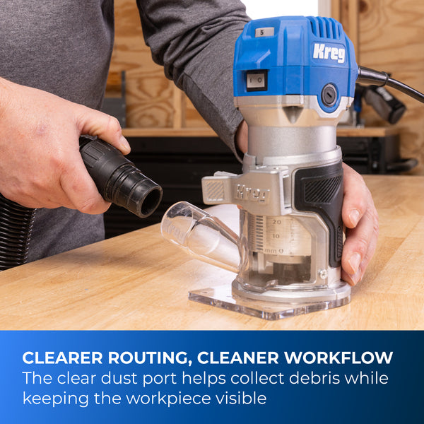Person using the Kreg trim router on a wooden work surface with a vacuum hose attached.