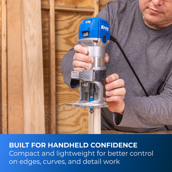 Blue Kreg trim router held by hands in a woodshop, showing the motor and base