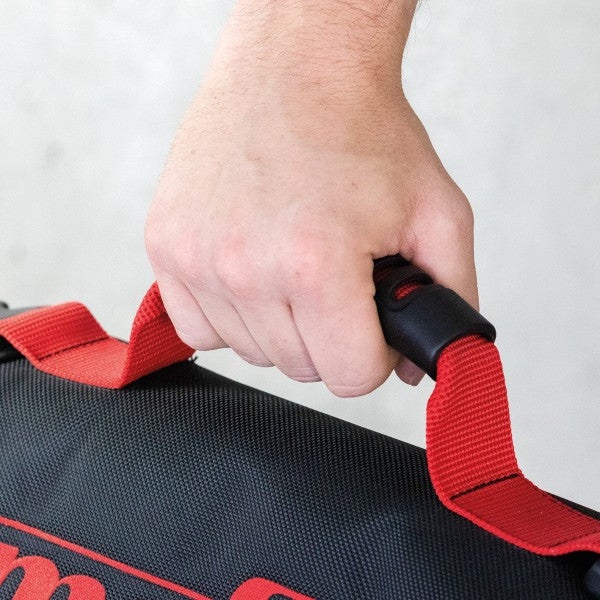 Hand gripping the red carrying strap of the Mafell tool bag.